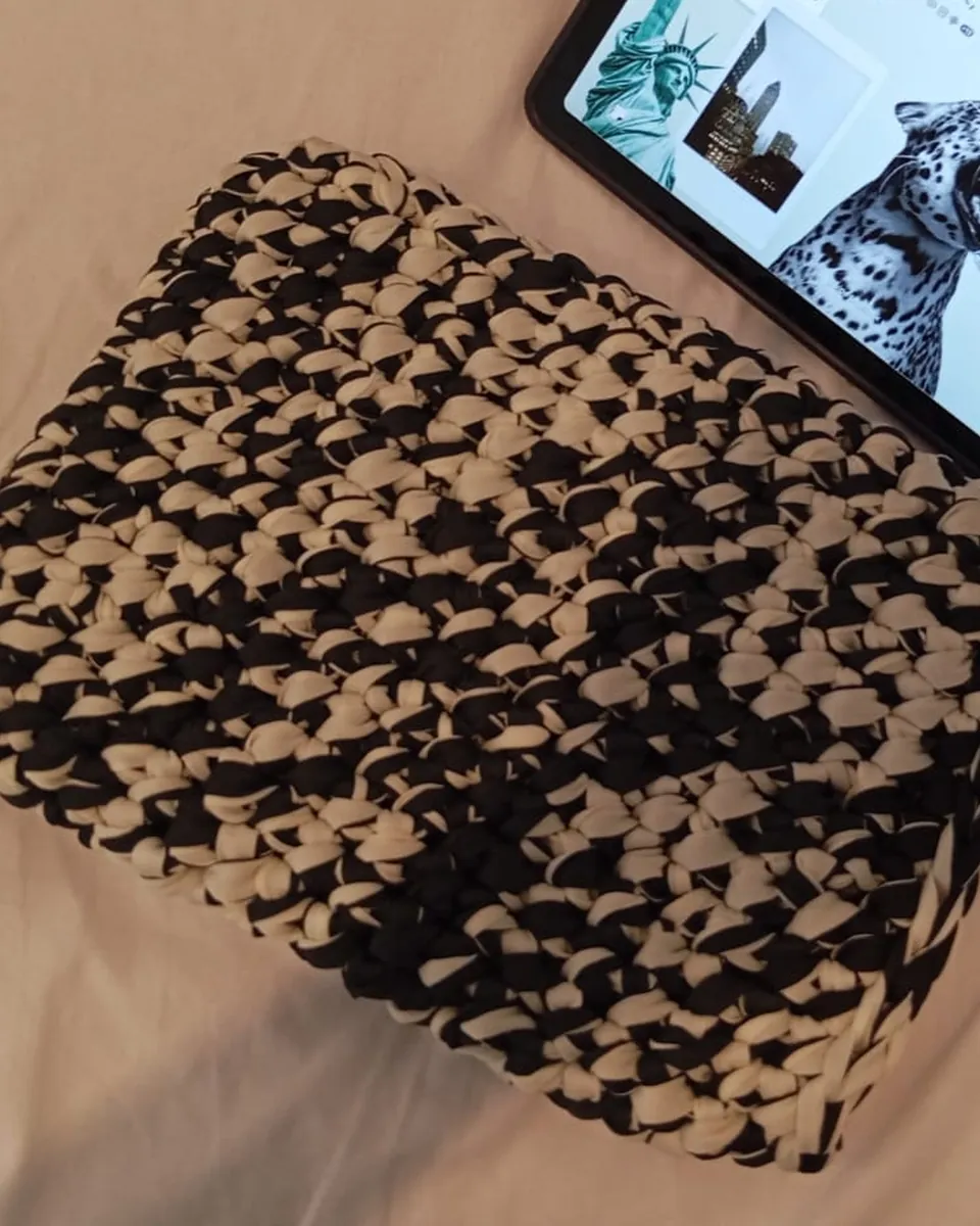 Funda de crochet en blanco y negro junto a una tablet